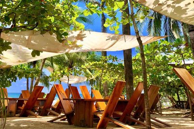 Beach chairs under the trees at Lola's, a seven-minute walk from Johnny's Beach Bungalow