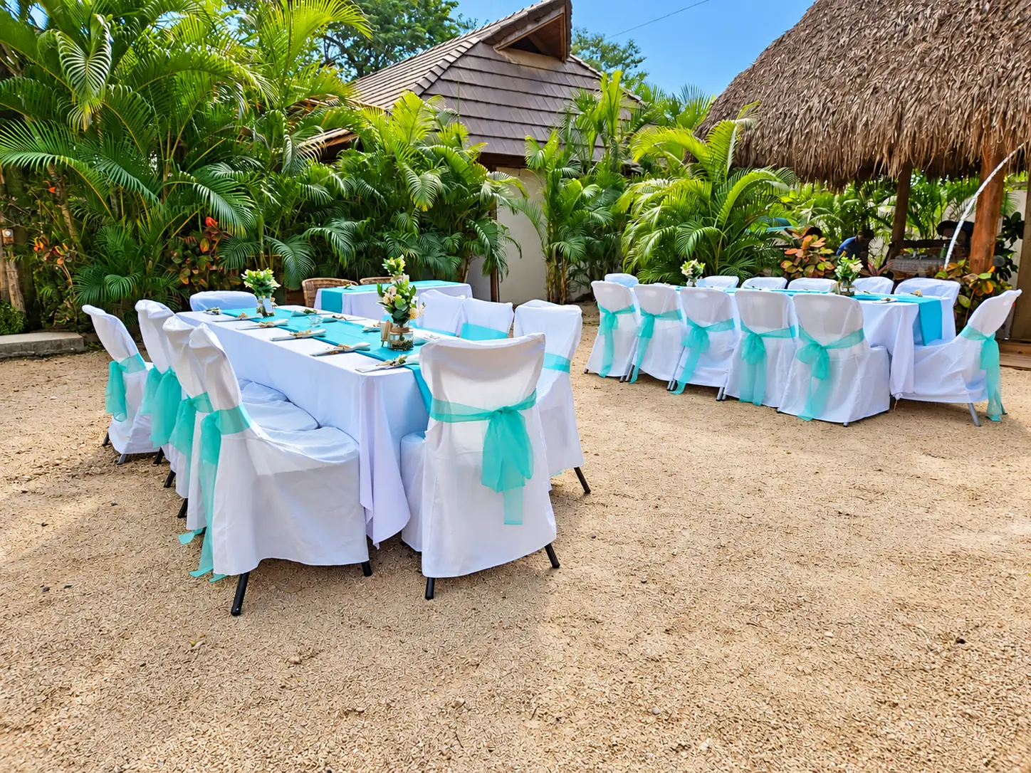 Reception tables with turquoise sashes set among palms at Johnny's Beach Bungalow in Guanacaste